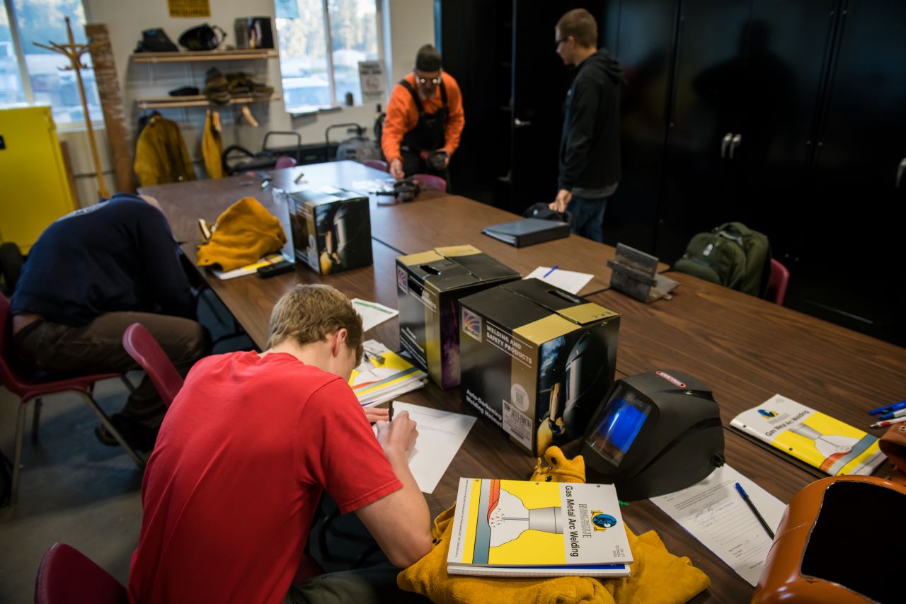 students in a welding classroom doing bookwork