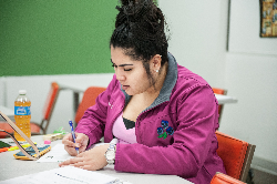 student writing at a table in class