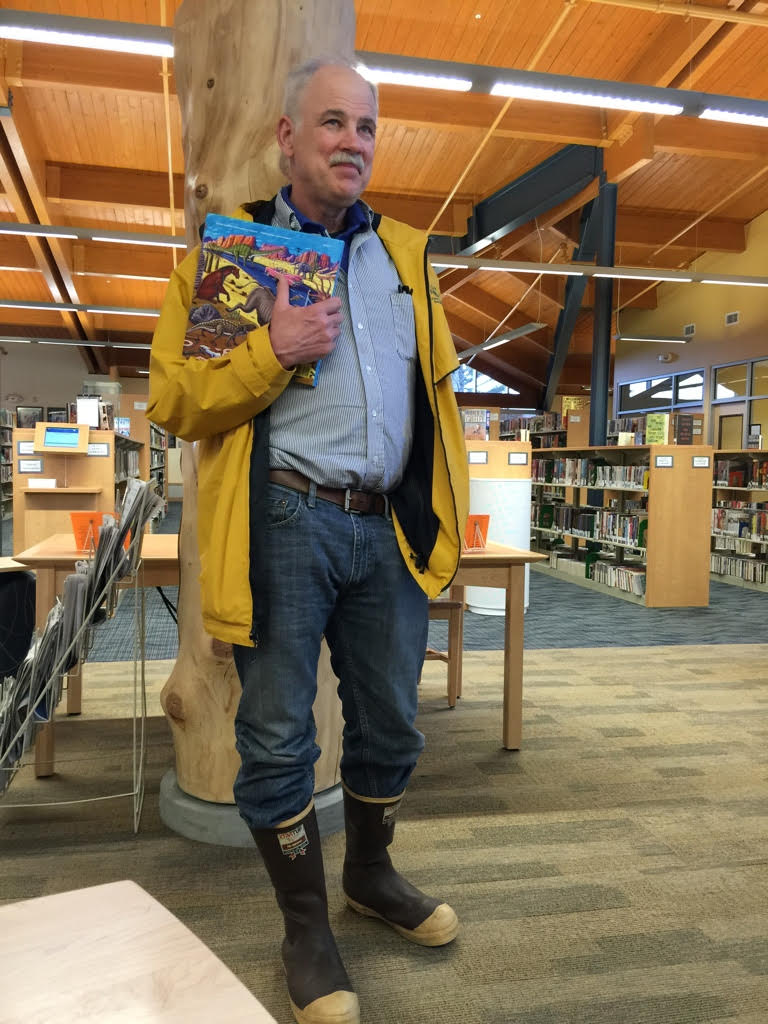 Bill Stenberg standing in a library holding a book