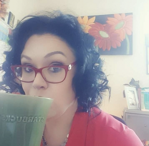 Jacelyn Keys wearing red glasses drinking out of a ceramic green mug 