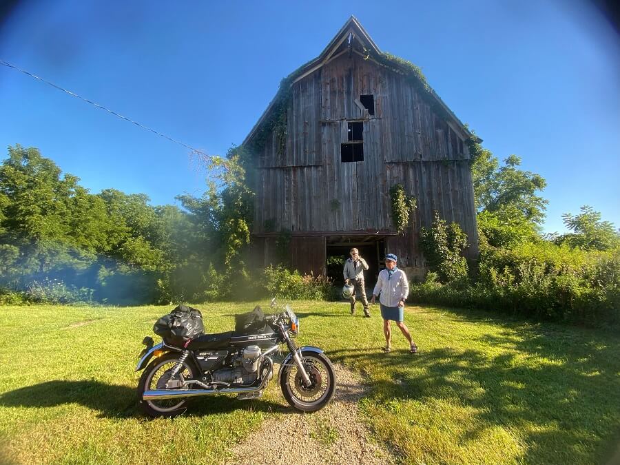 two people standing behind a Moto Guzzi motorcycle