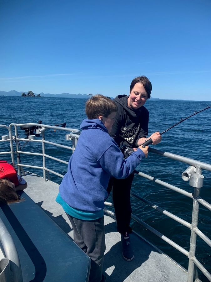 Kim saunders standing next to a child fishing off a boat
