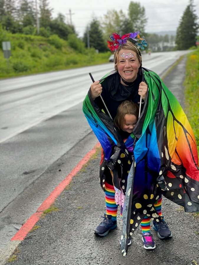 Kim Saunders enveloping a girl in a butterfly costume on a sidewalk