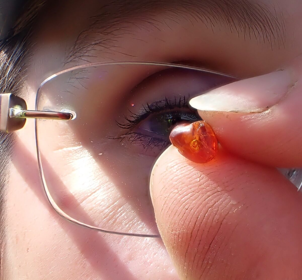 holding a piece of prehistoric amber up to her eye