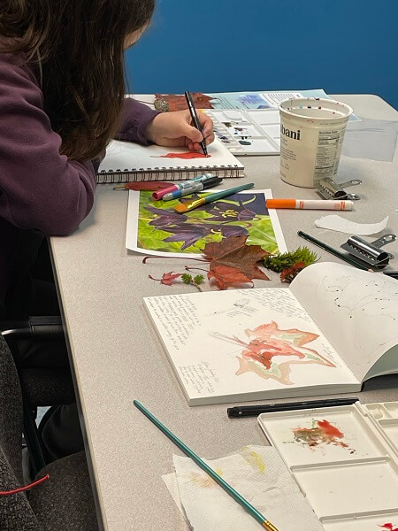 student in an art class painting in a nature journal