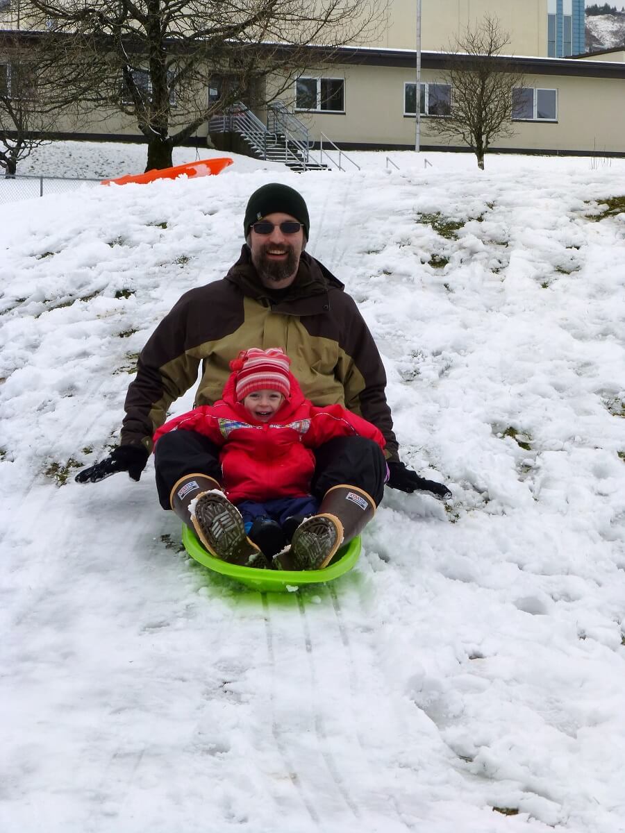 Taten Sheridan and a small child sledding down a snowy hill
