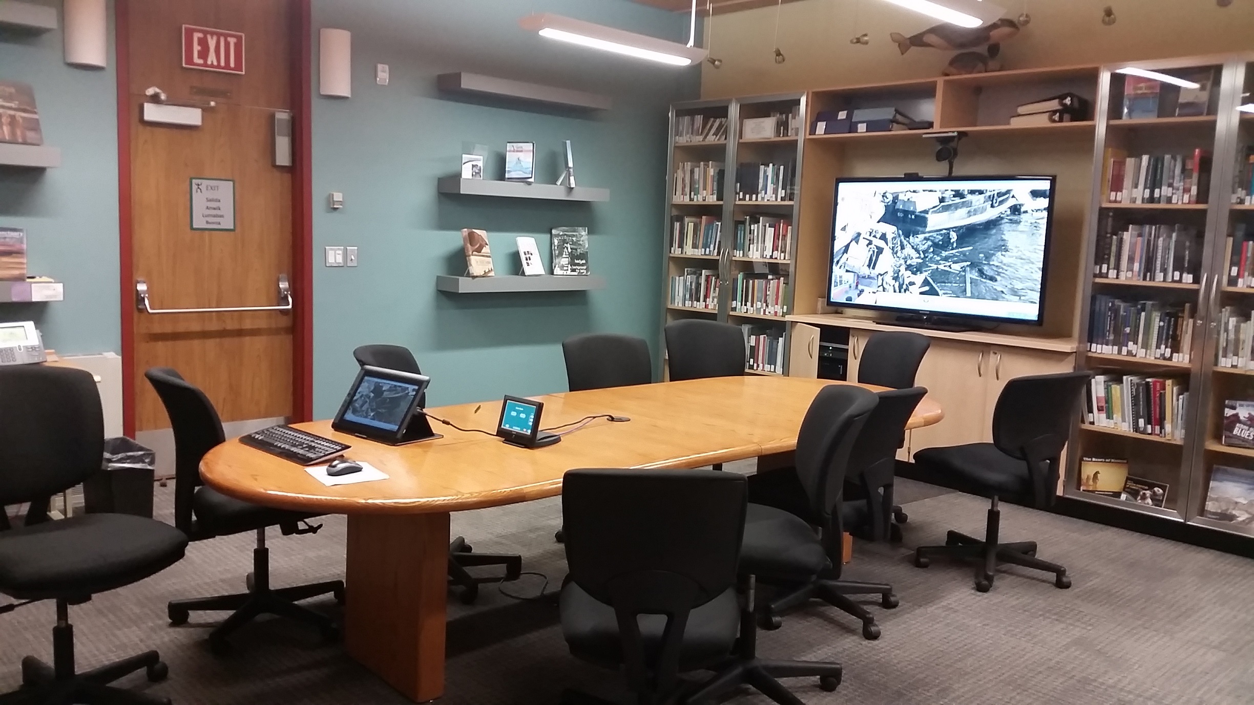 Panoramic view of the Kodiak room showing conference table, big screen tv, and bookshelves