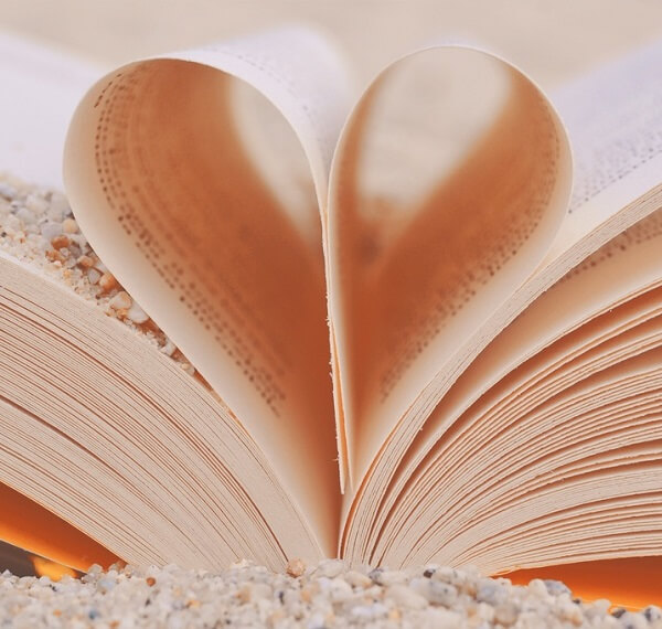A book on the sand with pages folded to look like a heart