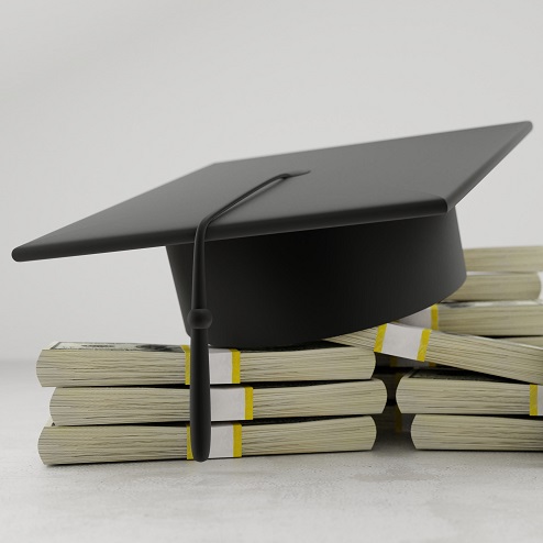 a black mortarboard on top of banded stacks of money