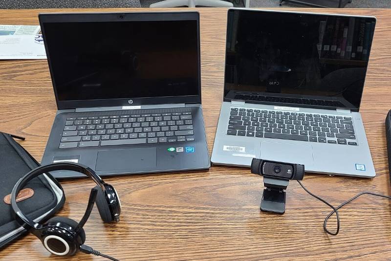 a laptop, chromebook, webcam, and headset on a table