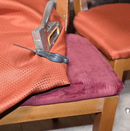 scissors and an upholstery stapler on a chair with fabric on top