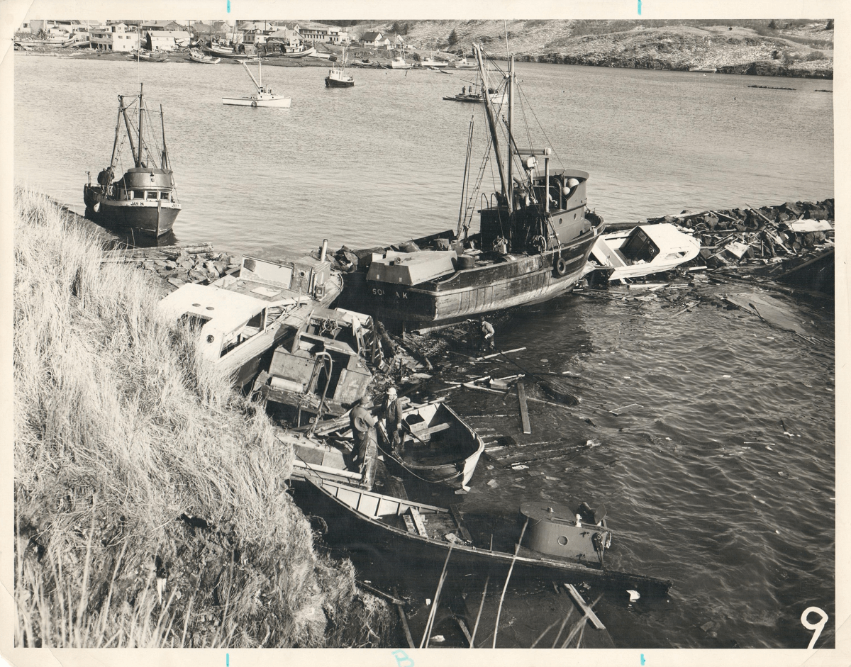 photograph of a fishing boat aground against a breakwater amidst debris and other boats