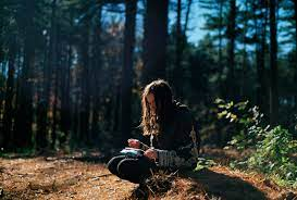 a woman writing in a journal in the forest