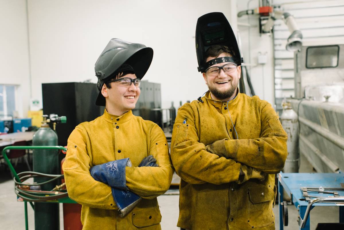 two students in welding clothing smiling